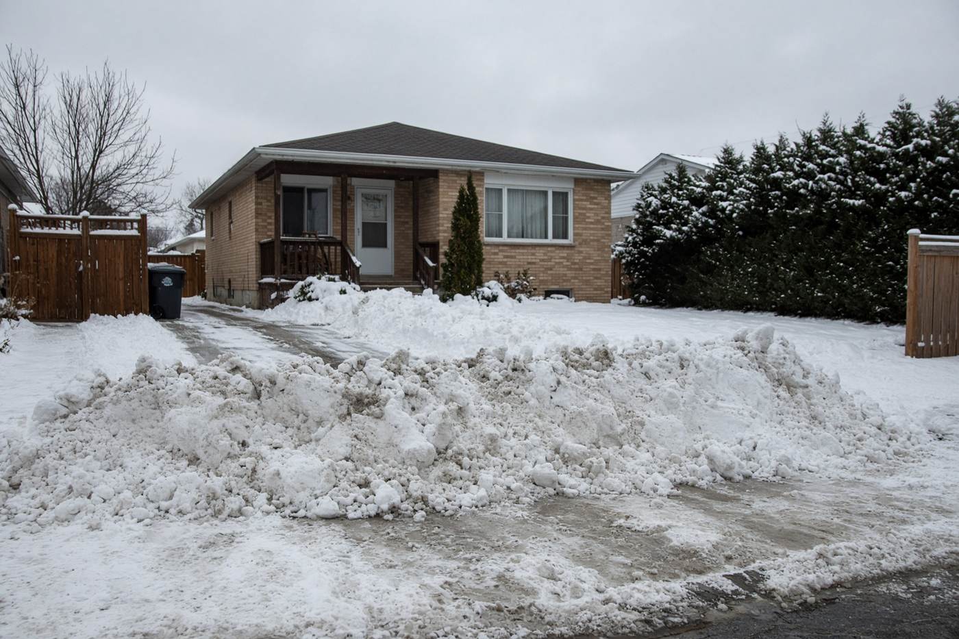 A packed ridge of snow left across the mouth of a driveway.